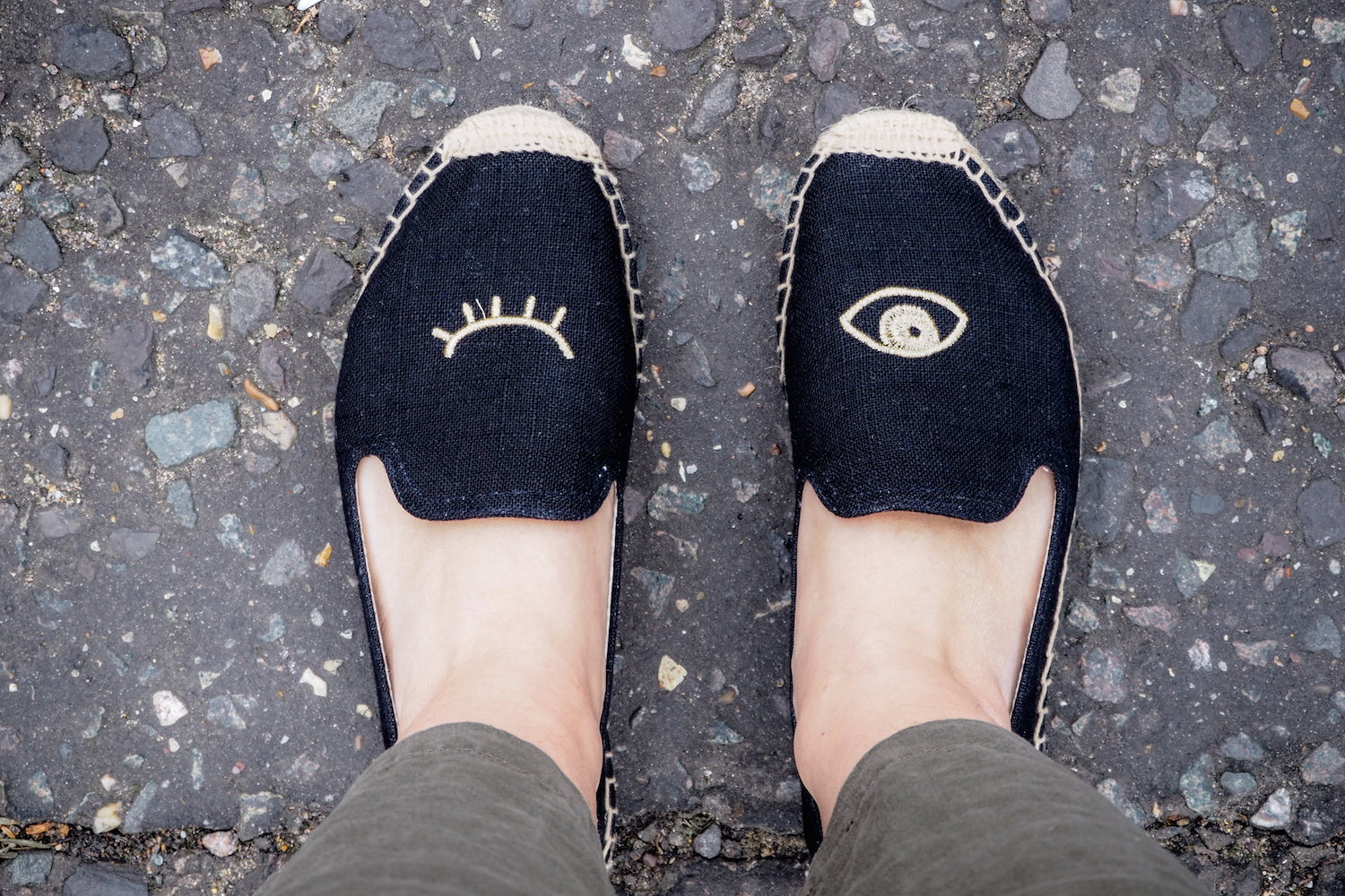 Two feet wearing winking eye black Soludos smoking slippers and the edge of linen trousers | Wolf & Stag